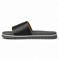 Men's single-band vegan leather slide sandal in matte black with white midsole stripe and tan piping detail, three-quarter view