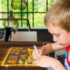 Child using GlowCraft LED drawing board with erasable markers creating bright glowing designs